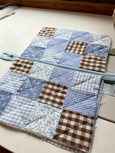 a blue and white patchwork quilt is being sewn on the table with scissors