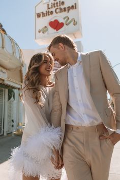 a man and woman standing next to each other in front of a sign that says little white chapel