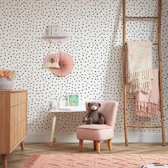 a child's room with polka dot wallpaper and pink chair