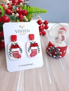 the christmas stocking earrings are on display next to a vase with berries and holly