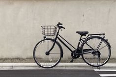 a bicycle parked next to a wall with a basket on the front and back tire