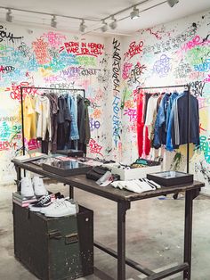 a clothing store with colorful graffiti on the walls and clothes on display in front of them