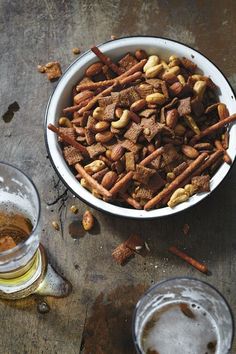 a bowl of food next to two glasses of beer