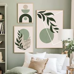 three green and white paintings hang on the wall above a bed in a living room