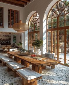 a dining room with large windows and wooden table surrounded by white cushions on the floor