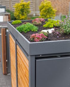 an outdoor planter with flowers and plants growing out of it