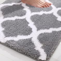 a person's feet on a gray and white rug