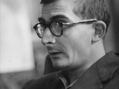 a black and white photo of a man with glasses looking off to the side in front of him