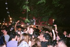 a large group of people standing around each other at a party with candles in the air