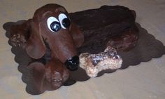 there is a chocolate cake with a dog on it and two doughnuts in front of it