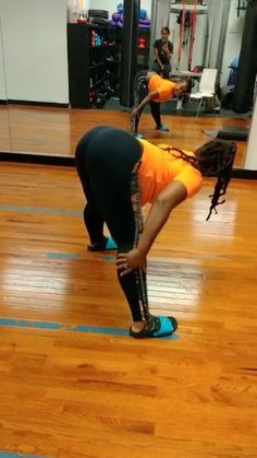 two people doing exercises in a gym with hard wood flooring and mirrors on the wall