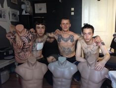 three male mannequins are posed in front of each other with tattoos on their bodies