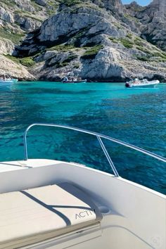 there is a boat that is in the water near some mountains and rocks on the shore