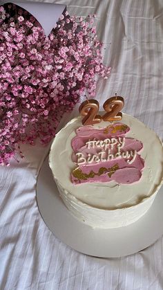 a birthday cake sitting on top of a table next to a bouquet of pink flowers