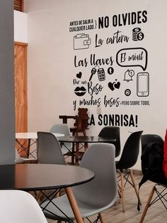 a woman sitting at a table in front of a wall with words written on it