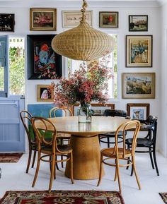 a dining room table with chairs and pictures on the wall