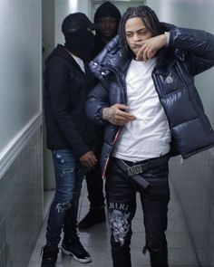 a man with dreadlocks standing next to two other men in an elevator area