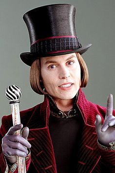 a man wearing a top hat and holding a lollipop in one hand while making the peace sign