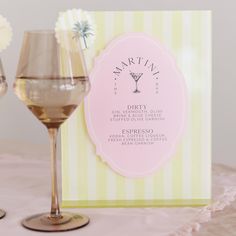 two wine glasses sitting on top of a table next to a card with the name martini