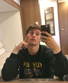 a young man taking a selfie in front of a mirror