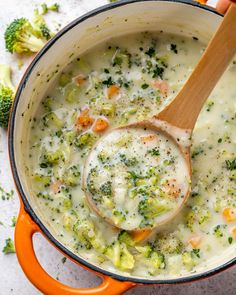 a wooden spoon in a pot filled with broccoli and cauliflower soup