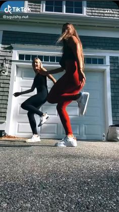 two women are dancing in front of a garage