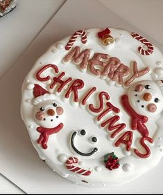 a white cake with red frosting and decorations on it that says merry christmas written in large letters