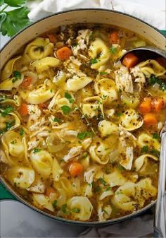 chicken noodle soup in a pot with a ladle and napkin on the side