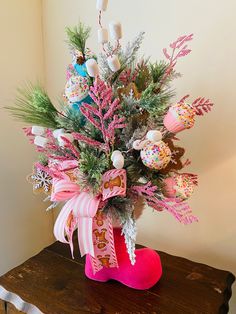 a christmas arrangement in a pink boot on a wooden table with snowflakes and candy