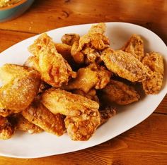 fried food on a white plate sitting on a wooden table