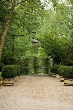 an iron gate with two planters in front of it and a light hanging over the entrance