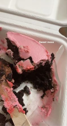 a half eaten cake with pink frosting in a white container