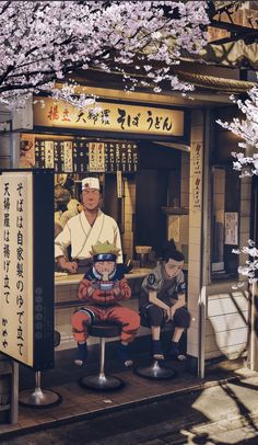 a man sitting on a bench in front of a store with cherry blossoms around him