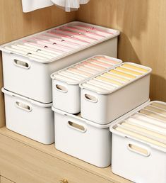 three white storage bins sitting on top of a dresser