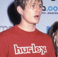 a young man in a red shirt standing next to a woman