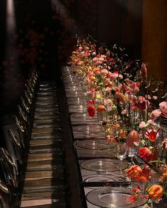 the long table is set with many clear vases and flowers on each one side