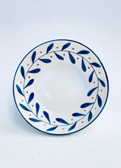 a white plate with blue and red designs on the rim is sitting against a white background