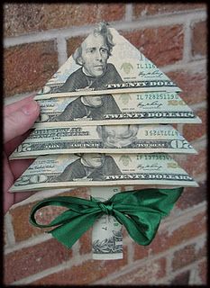 someone is holding up a christmas tree made out of dollar bills and tied with a green ribbon