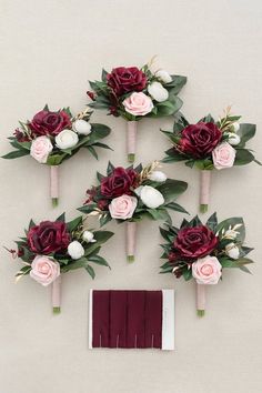 wedding bouquets with burgundy and white flowers are arranged on the wall