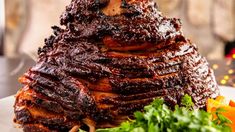 a large piece of meat sitting on top of a white plate next to some vegetables