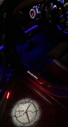 the interior of a car is lit up with blue light and features an illuminated steering wheel