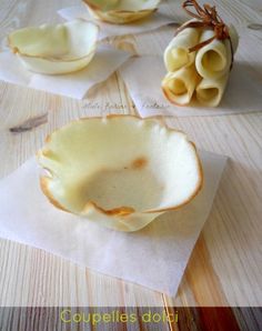 three bowls and two spoons sitting on top of a wooden table with napkins