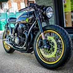 a black and yellow motorcycle parked in front of a building with its wheels turned to the side