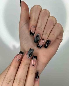 a woman's hands with black and white manies on their nails, one holding the