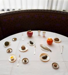 a table topped with plates and silverware next to an apple