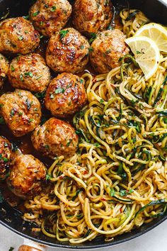 spaghetti and meatballs in a skillet with lemon wedges on the side, ready to be eaten