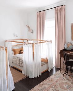 a bedroom with pink curtains and white bedding