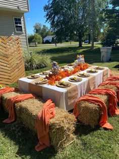 a table set up with hay bales and orange napkins