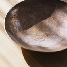 a metal bowl sitting on top of a wooden table