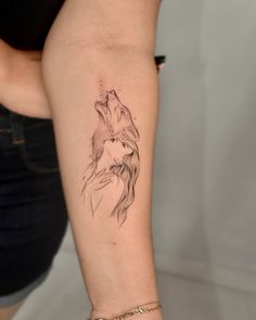 a woman's arm with a tattoo of a wolf and her head in the air